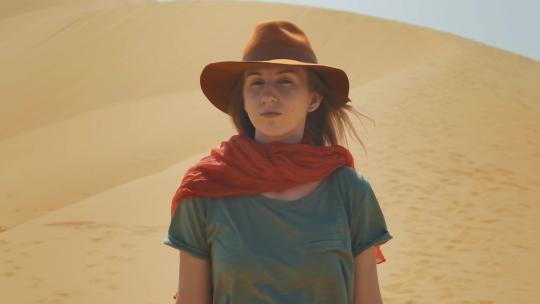 戴着牛仔帽的女孩走在沙漠中