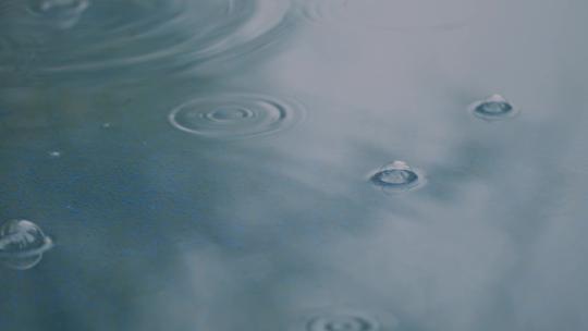 下雨天滴在水坑里的雨滴泛起涟漪视频素材模板下载