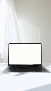 笔记本电脑放在白色桌子上竖屏