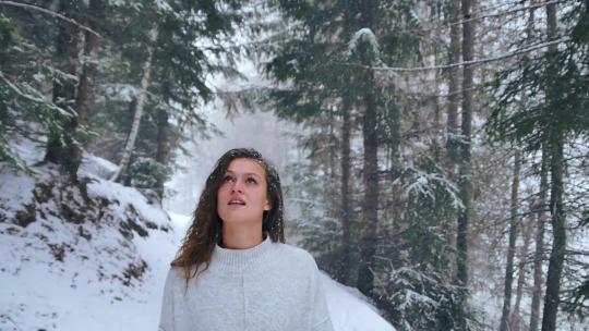 女人走路扔了一片白雪覆盖的森林，环顾四周美丽的风景