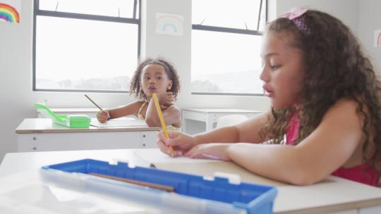 混血女孩坐在学校课桌前学习的视频