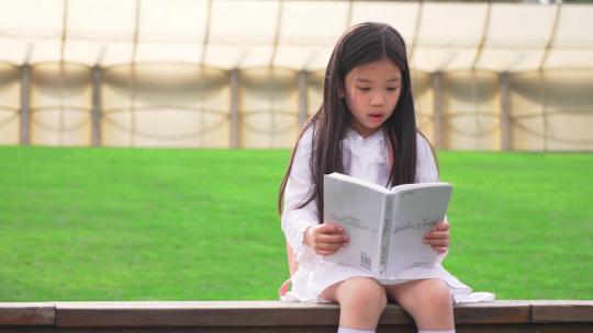 在操场认真读书看书的小女孩
