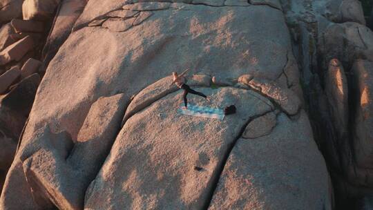 一个女人在海岸线上的岩层上做瑜伽练习