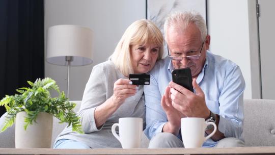 老年夫妻使用智能手机和信用卡