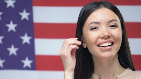 美丽的年轻女子微笑的相机在美国国旗背景，爱国主义