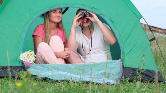 夫妇帐篷内用望远镜观看远处