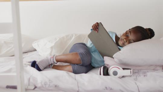 微笑的非裔美国女孩在家里的双层床上使用平板电脑，复制空间视频素材模板下载