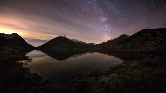 阿尔卑斯山的夜空，时间流逝银河系的恒星在山脉上旋转