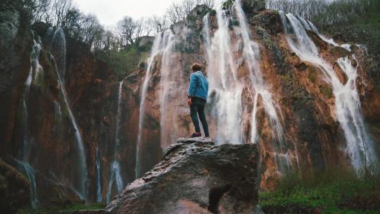 男子站在瀑布下方的岩石上