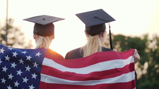 两名身着美国国旗礼服和帽子的大学毕业生视频素材模板下载