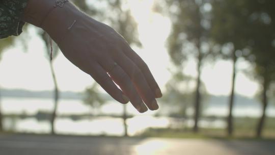 男人的手牵着女人的手，订婚戒指在日出。情侣的手互相握着。