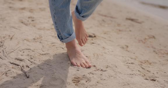 女性的腿赤脚去沙子