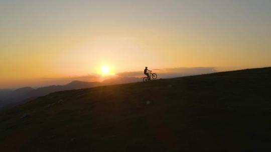 夕阳下一男子在山上骑行