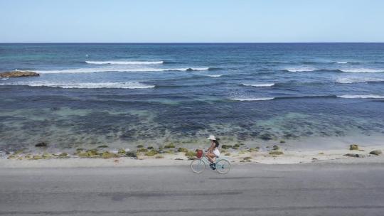 航拍在海边骑自行车的女性高清在线视频素材下载