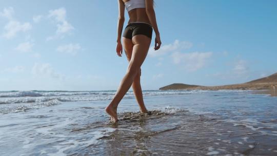 女人赤脚走在夏日海滩上