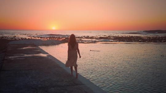 夕阳西下美女散步于海岸边