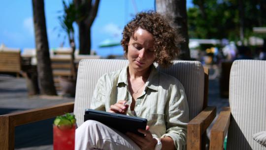一个美丽的自由职业者女孩坐在街头咖啡馆里，通过互联网远程提供软饮料
