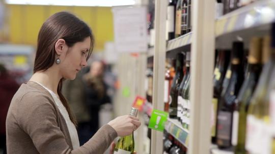 女人挑选商店货架上的葡萄酒