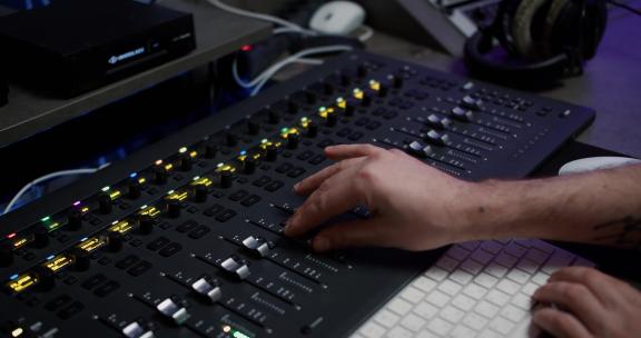 一位声音制作人正在录音室使用带有编辑工具的音乐混音器