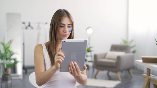 年轻可爱女人坐在家里从平板电脑上得到好消息的肖像视频素材模板下载