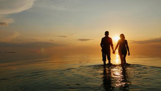 情侣在夕阳的海边漫步