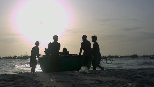 渔民将圆船拖到海滩