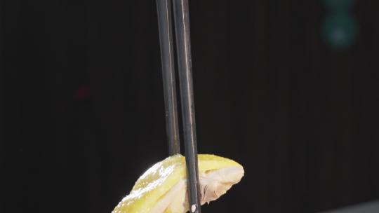 筷子夹起白切鸡肉汁特写