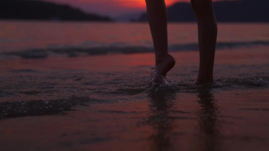 女孩在日落海滩边赤脚行走
