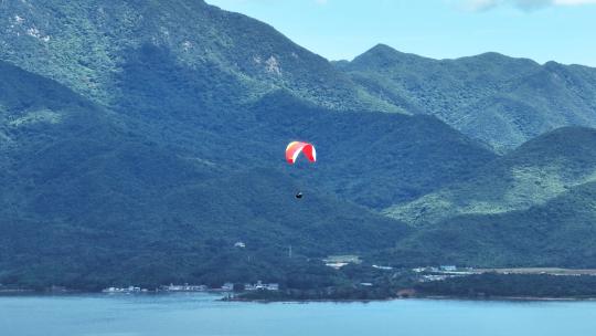 航拍蓝色海洋上飞行的滑翔伞极限运动