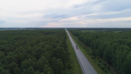 晚上10点，无人机航拍了一辆卡车和汽车在山丘附近的夏季森林路上
