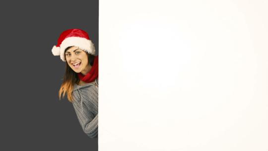 美女戴着圣诞帽子指向白色海报