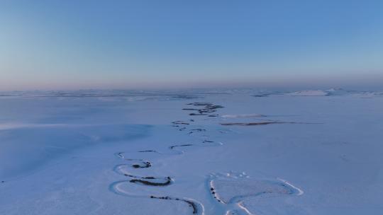 航拍雪原上蜿蜒的冰封河流暮色