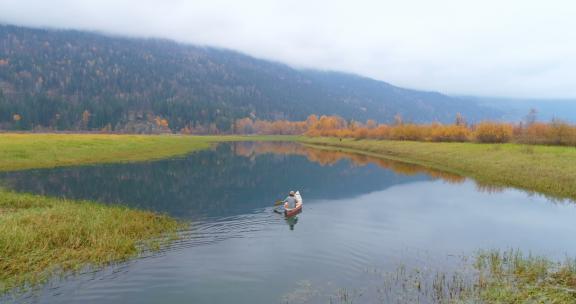航拍一个人和他的狗在湖上划船