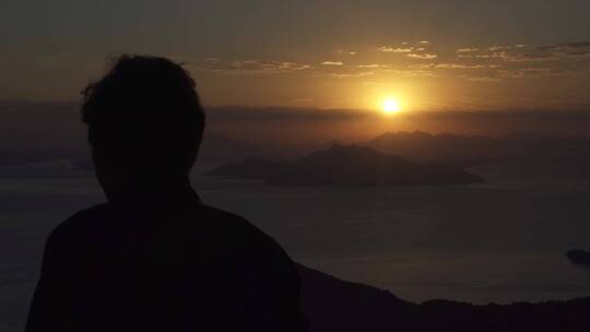 一个在山顶上看地平线上日落的男人