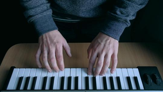 音乐家双手弹奏电子琴。