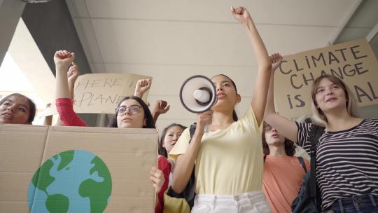 多民族青少年团体在抗议游行中举着环境和保护标志
