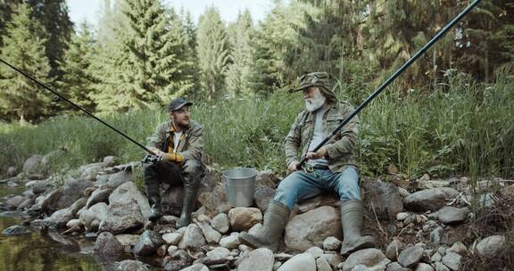 两个男人坐在河边一边钓鱼一边聊天
