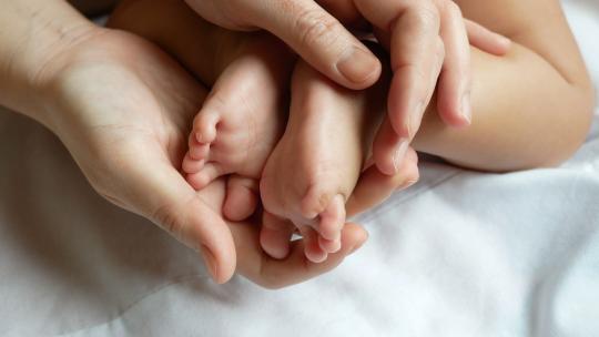 一双手轻轻抚摸婴儿的小脚