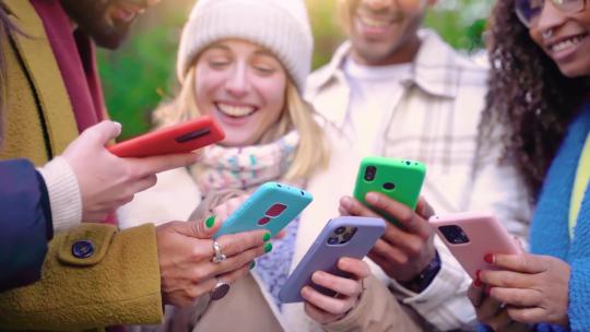 一群年轻的青少年朋友使用手机，在沉迷于技术的城市里行走。
