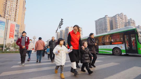 城市交警指挥交通、志愿者带小朋友过马路