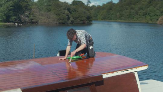 年轻的木匠在清漆上打滚，刷木船的船舱屋顶