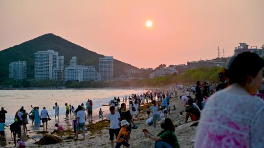 三亚大东海景区沐浴在夕阳余晖下的游客市民