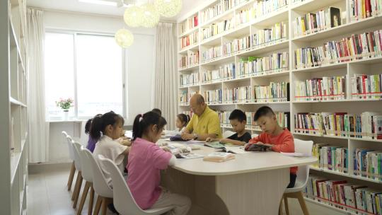 老师带小学生在图书馆看书