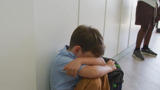 男孩坐在学校走廊上哭泣