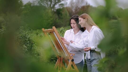 两个女人一起在户外画布上作画