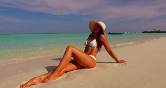 美丽的美女模特在天堂白沙和蓝色背景的海滩上晒太阳旅行