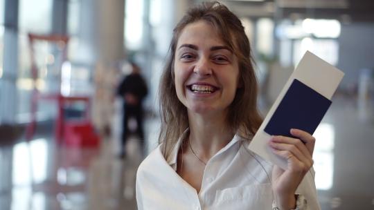 快乐美丽的美国女人的肖像展示护照和机票并挥舞它视频素材模板下载