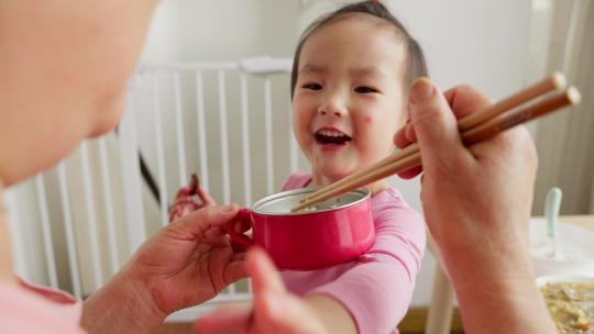 小女孩在家里吃饭大人用筷子喂饭
