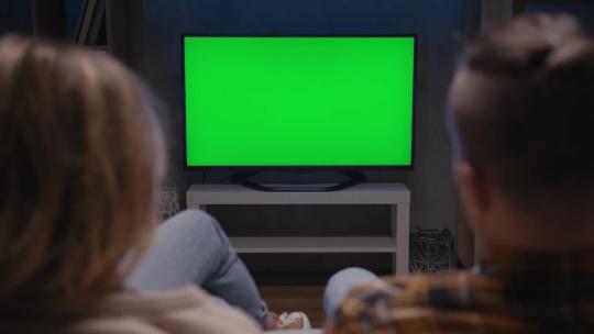 夫妻坐在客厅的沙发上看绿屏电视视频素材模板下载