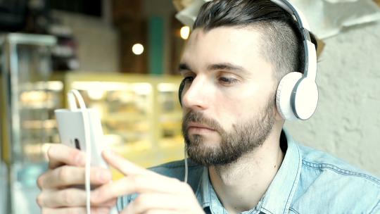 英俊的男人在咖啡馆用耳机听音乐时看起来很放松